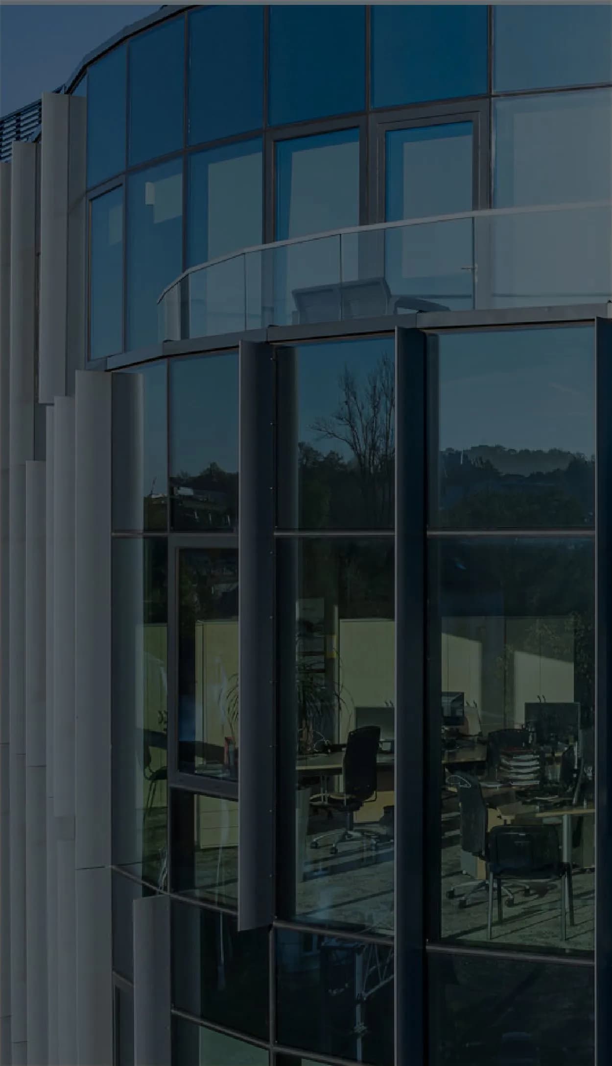 Close-up of a modern glass office building with curved facade.